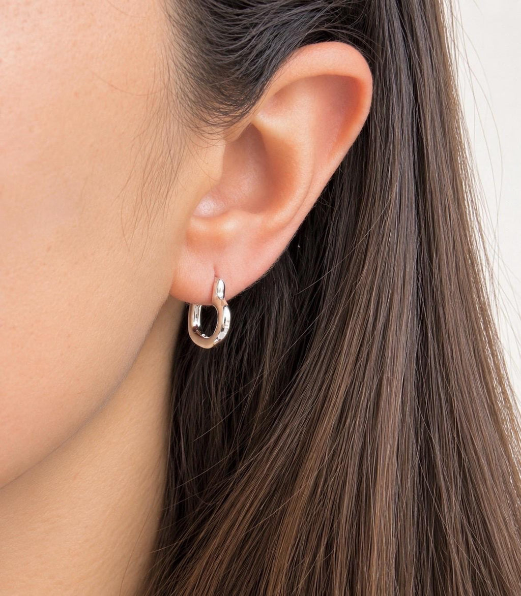 Silver heart-shaped hoop earring worn on the ear