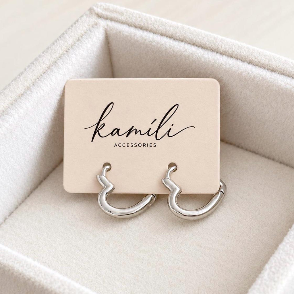 Pair of silver heart hoop earrings on Kamíli Accessories branded jewellery card