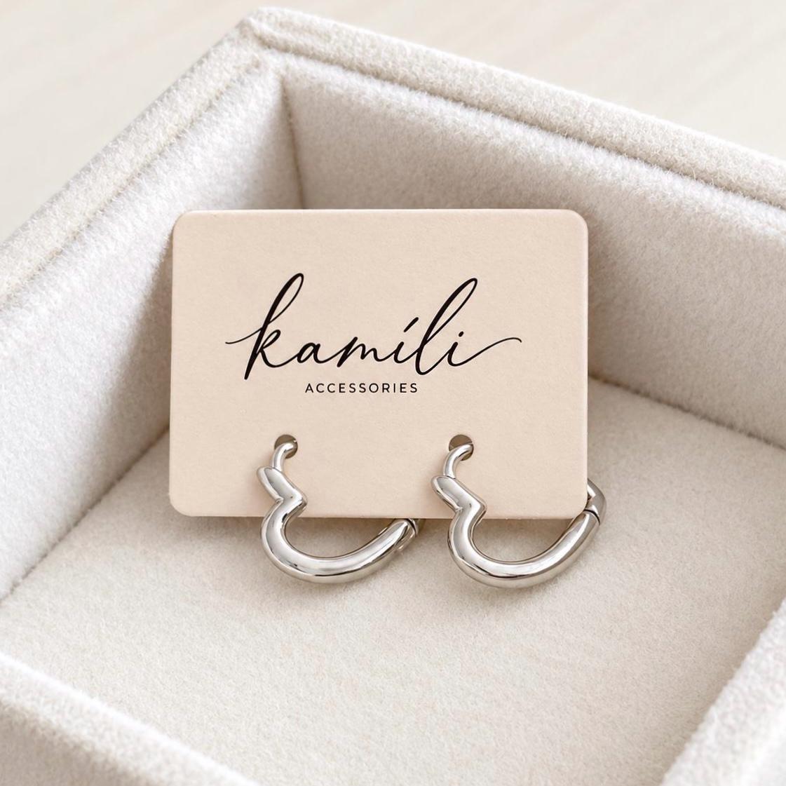 Pair of silver heart hoop earrings on Kamíli Accessories branded jewellery card