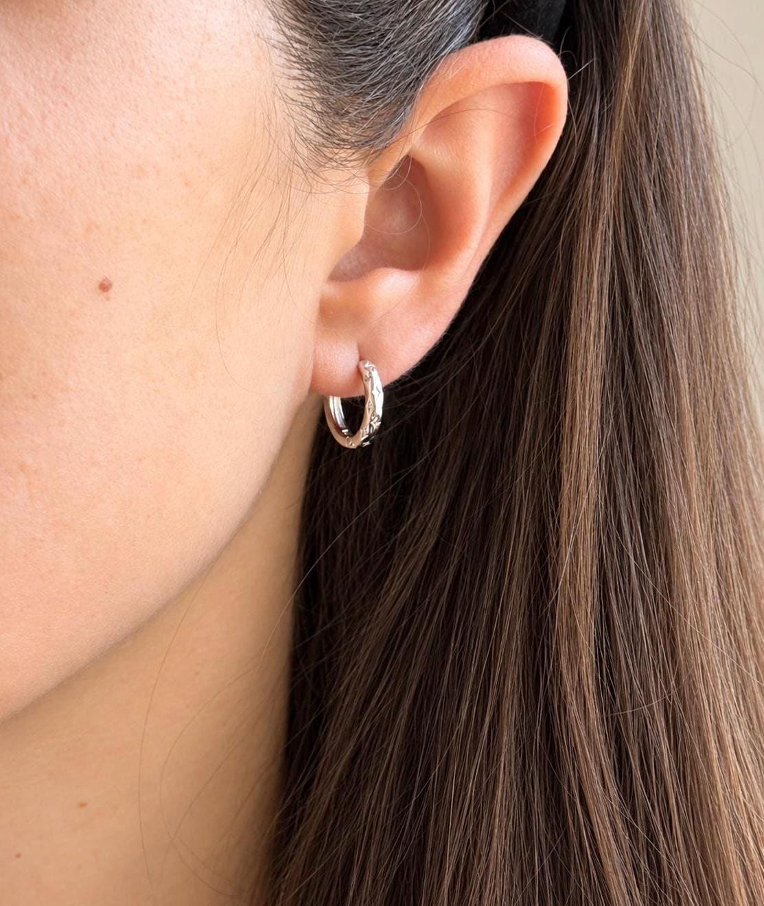 Model wearing 925 sterling silver star engraved huggie earrings