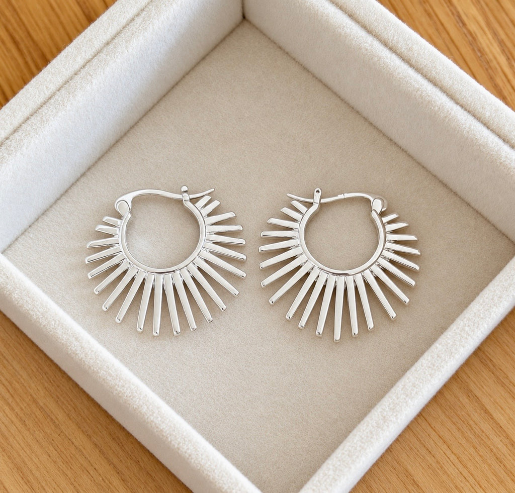 Pair of polished silver sunburst hoop earrings in cream jewellery box