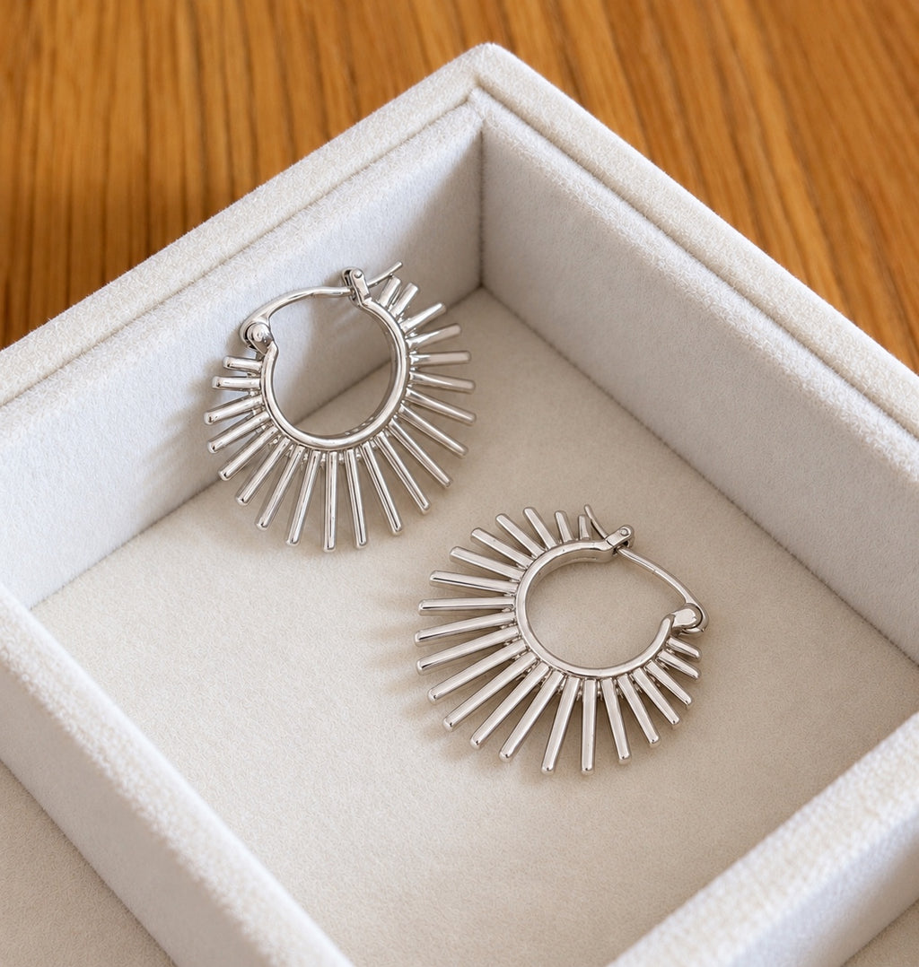 Overhead photo of sterling silver sunburst hoops in cream jewellery tray