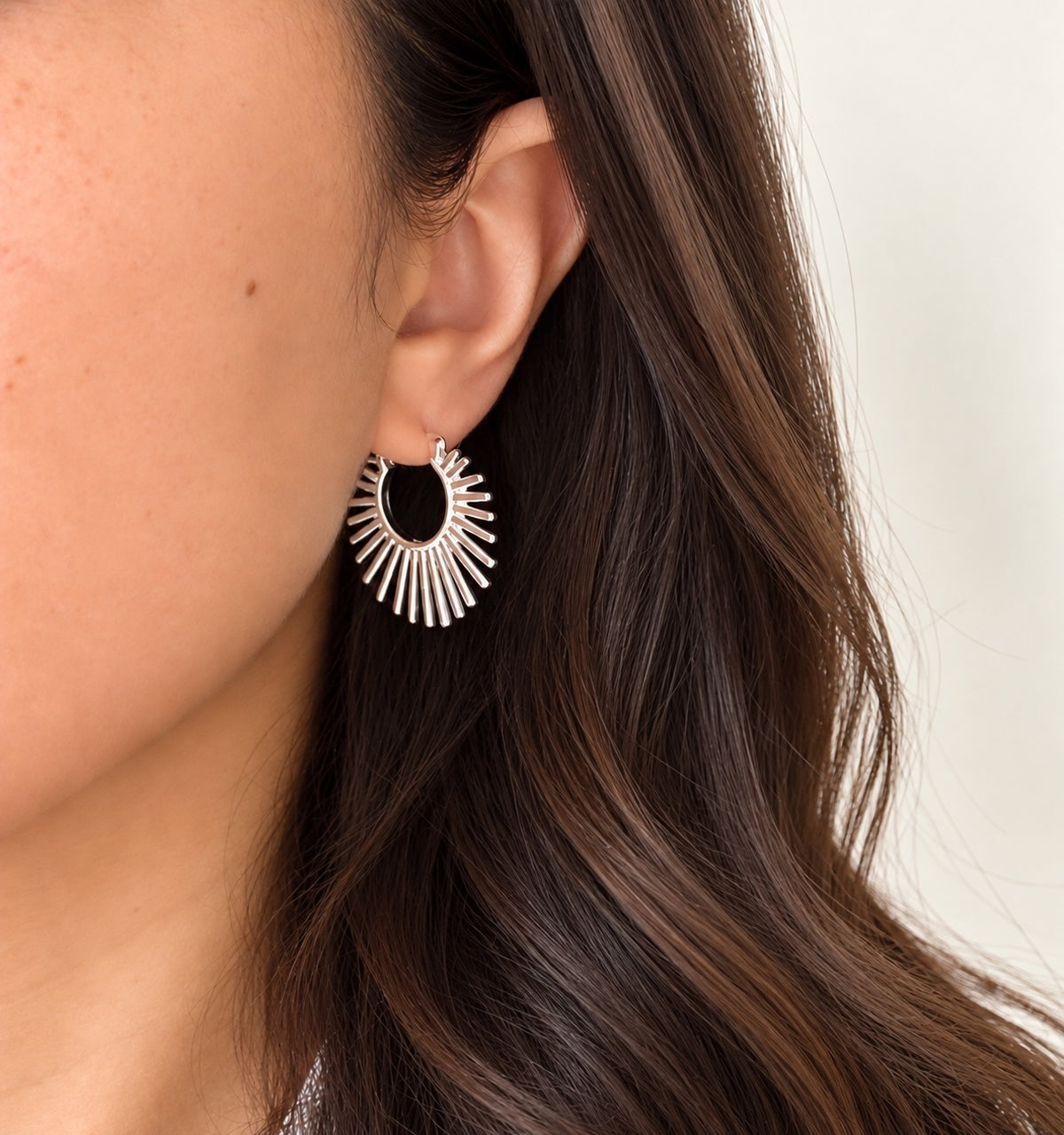 Sunburst sterling silver hoop earrings worn on the ear