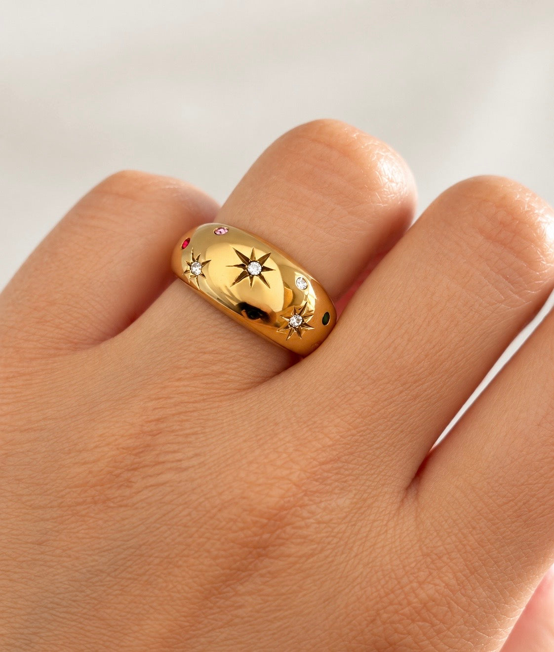Chunky gold celestial starburst ring worn on finger, close-up
