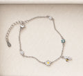Sterling silver daisy and bee charm bracelet with delicate floral motifs on ivory velvet