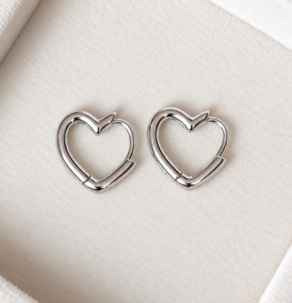Front detail of polished silver open heart hoop earrings