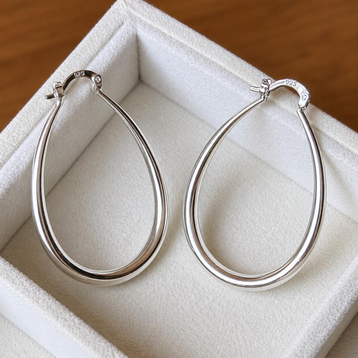 925 sterling silver pear-shaped teardrop hoop earrings, product close-up on ivory velvet