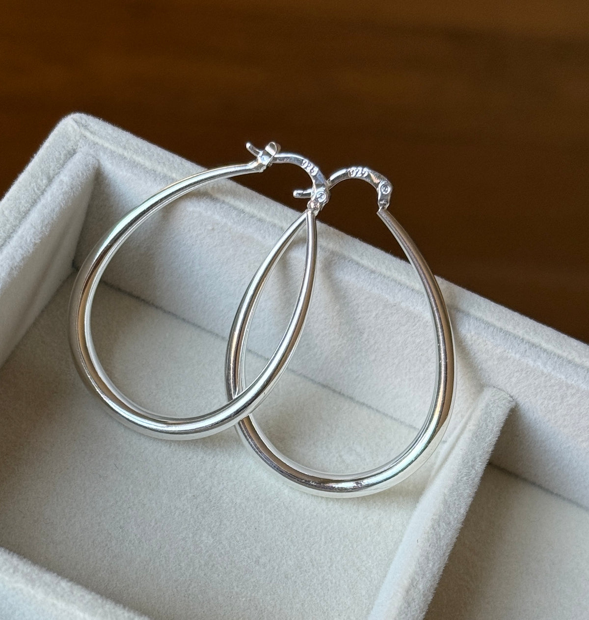 Pair of sterling silver teardrop hoops showing secure hinged clasp