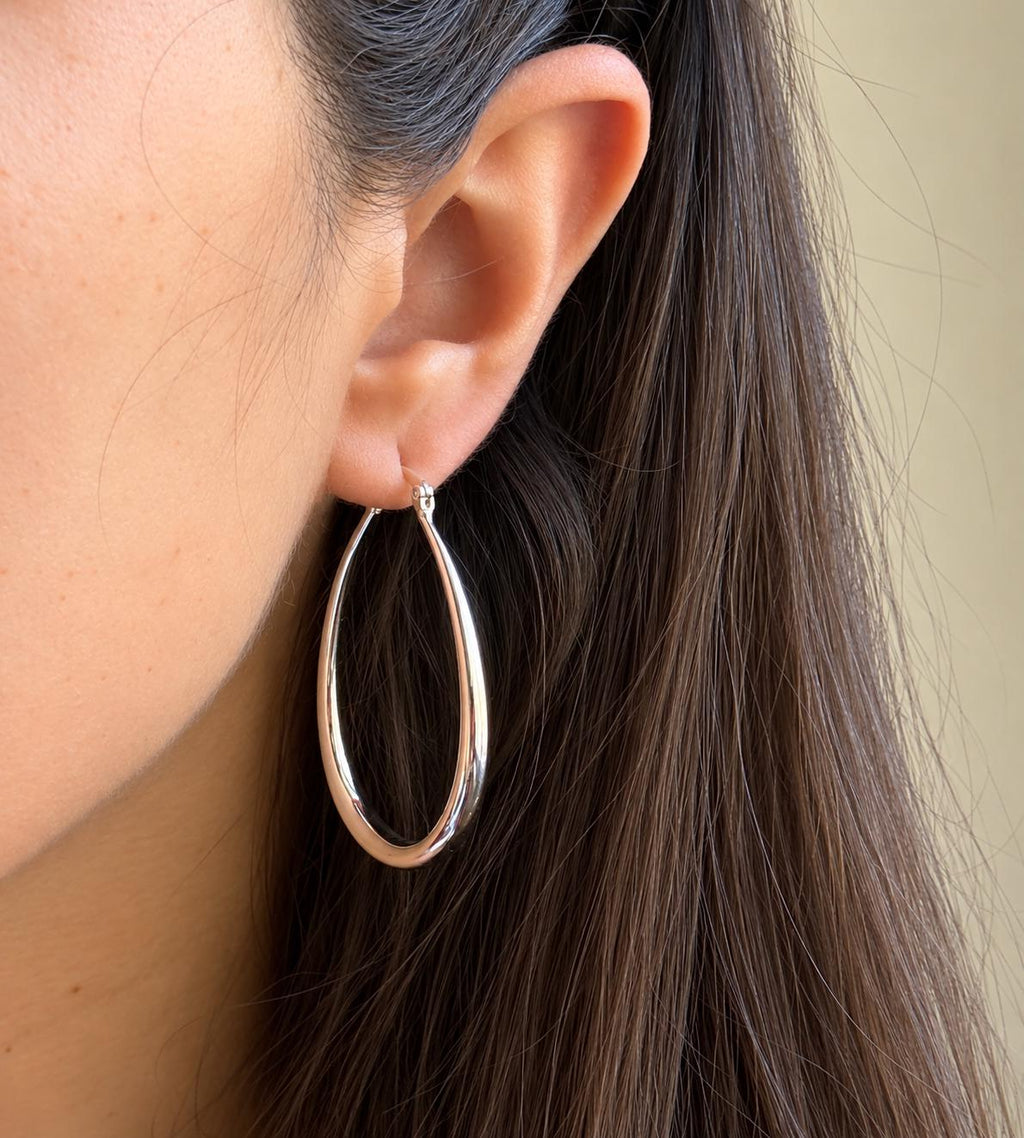 Long silver teardrop hoop earring worn on ear to show scale
