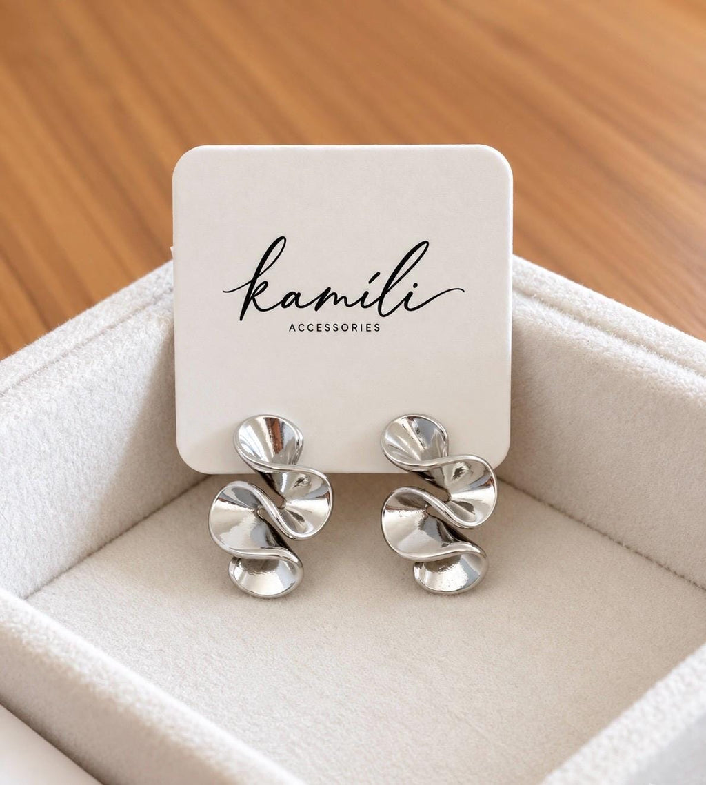 Pair of polished abstract swirl stud earrings on Kamili Accessories jewellery display card