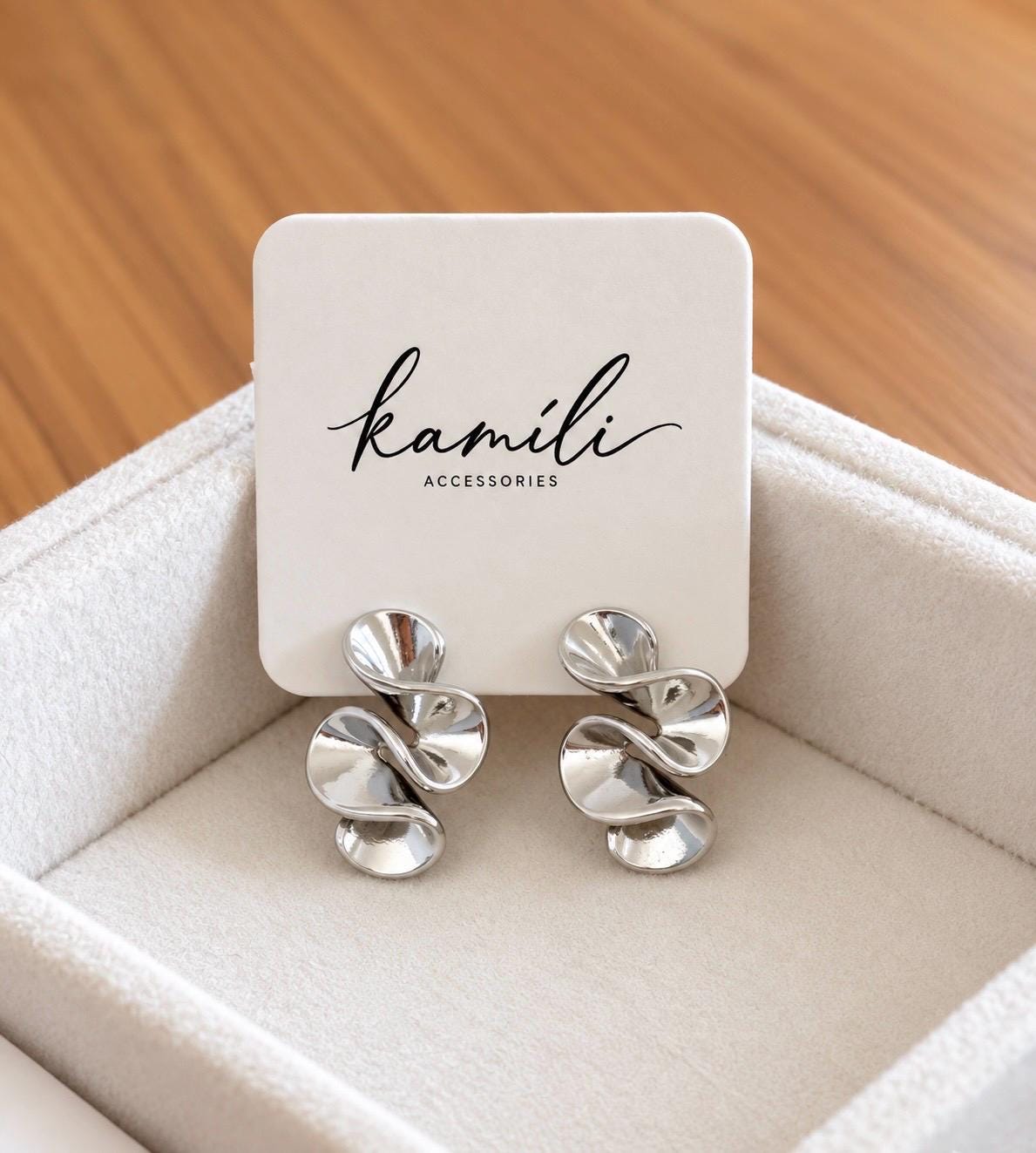 Pair of polished abstract swirl stud earrings on Kamili Accessories jewellery display card