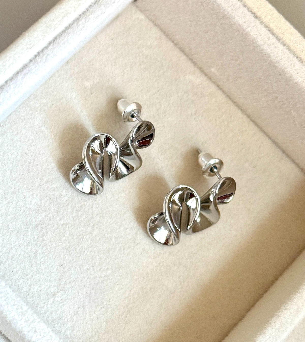 Back and side view of silver-colour abstract swirl stud earrings with butterfly backs