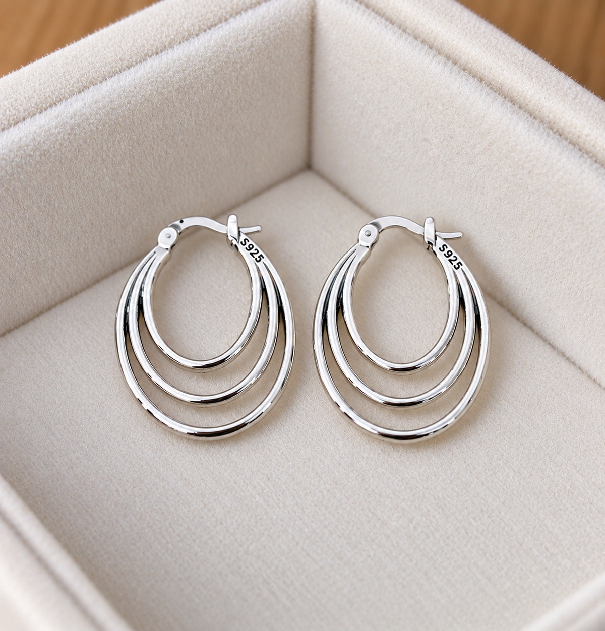 Pair of triple-layer oval 925 sterling silver hoop earrings displayed in an ivory velvet jewellery box