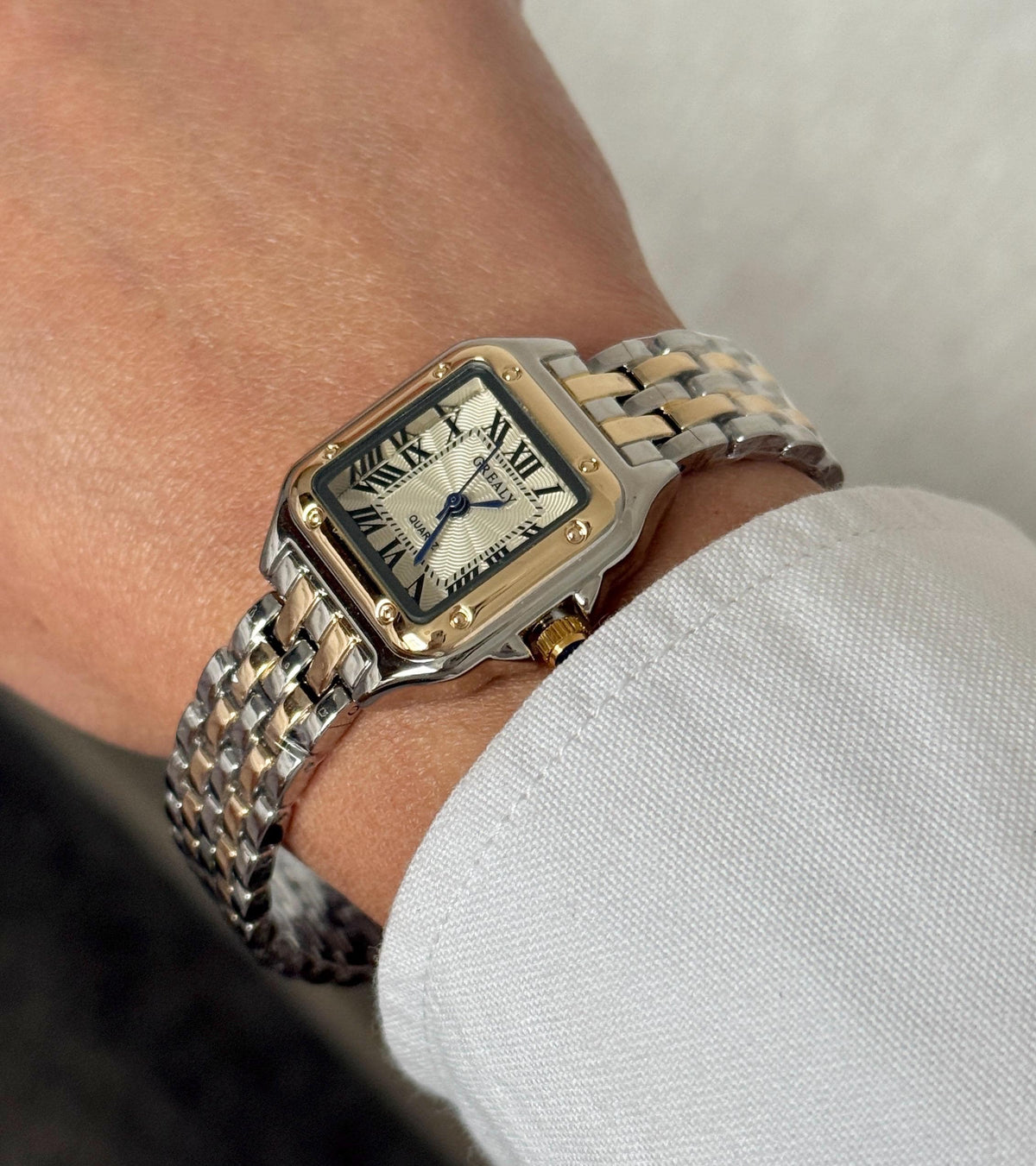 Close angled view of two-tone silver and gold square watch with Roman numeral dial